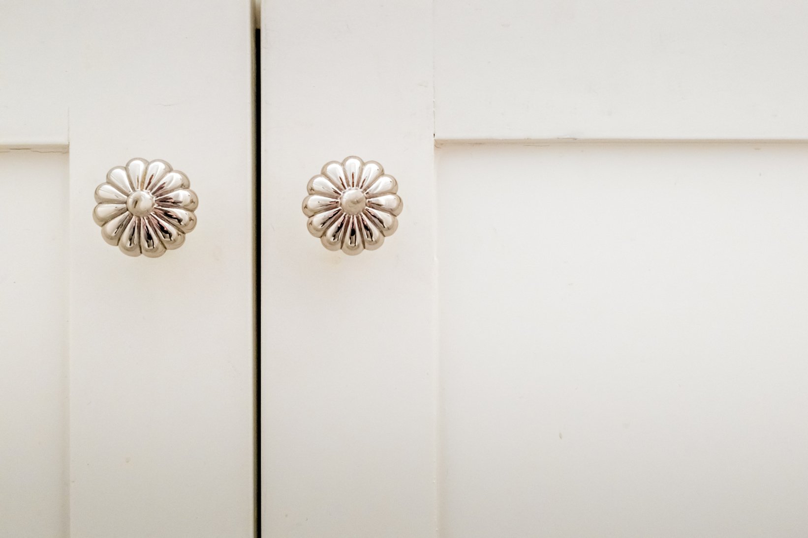 Decorative silver door knobs on white cabinet doors